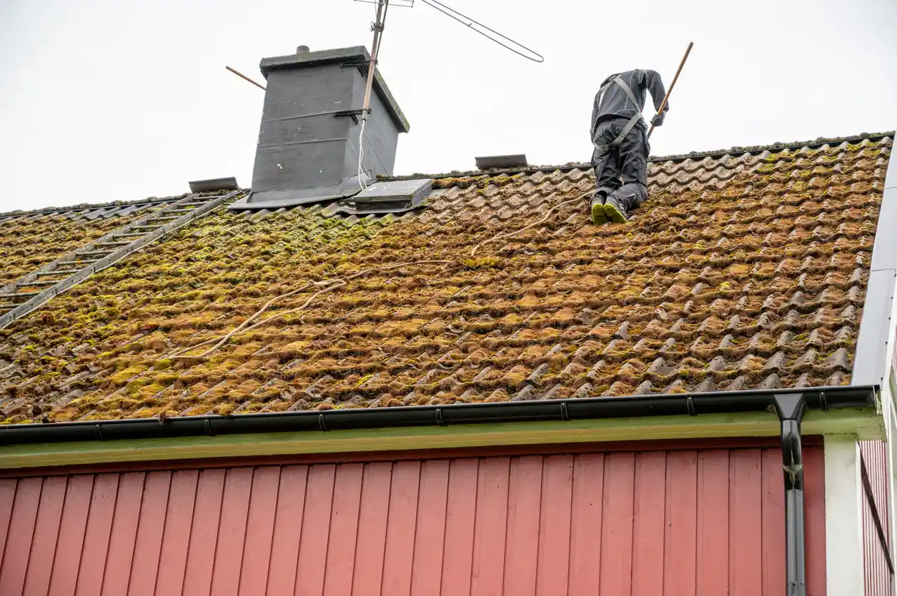Couvreur nettoyant toit au balai